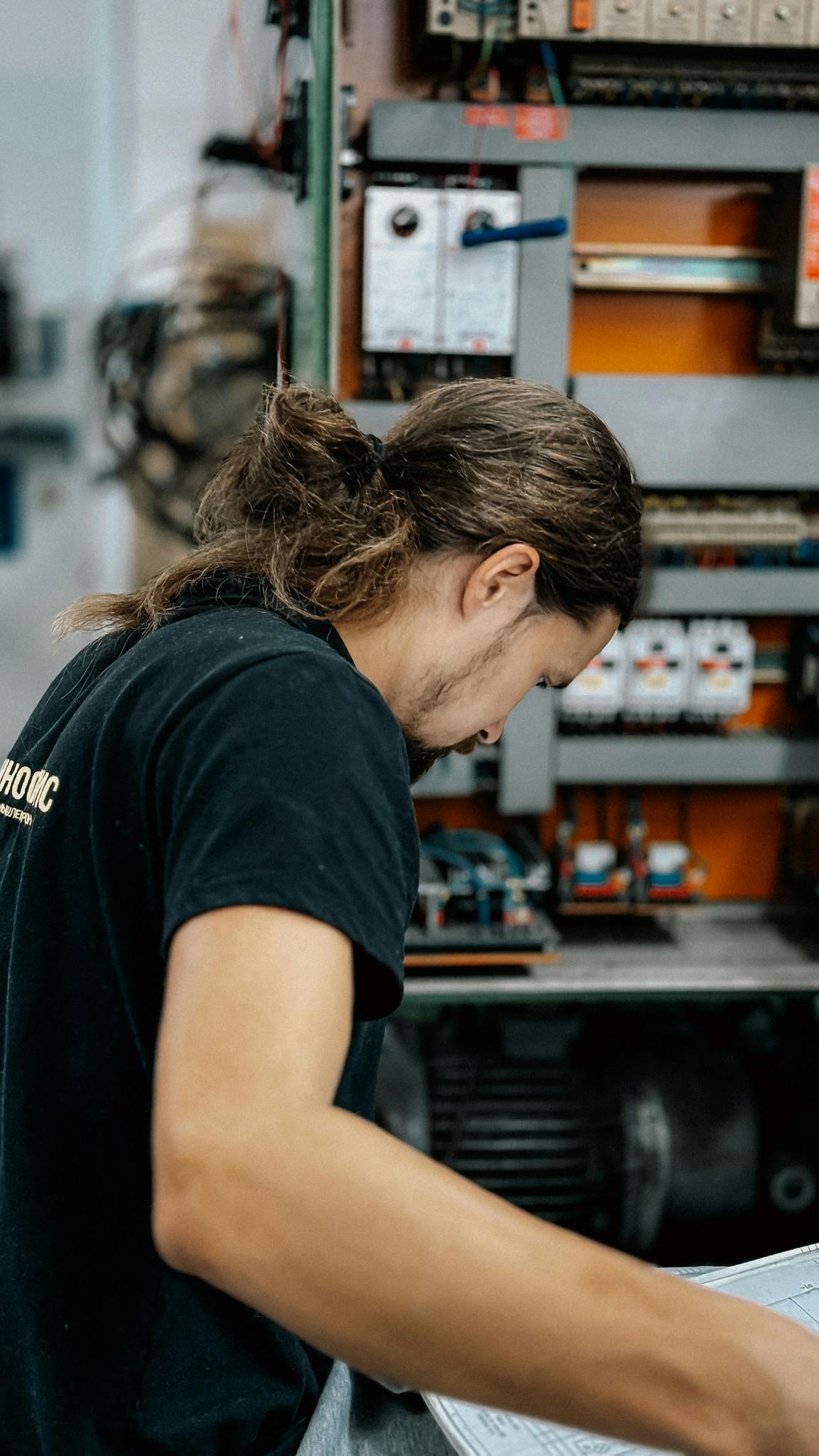 Male technician inspecting an electrical panel for maintenance.